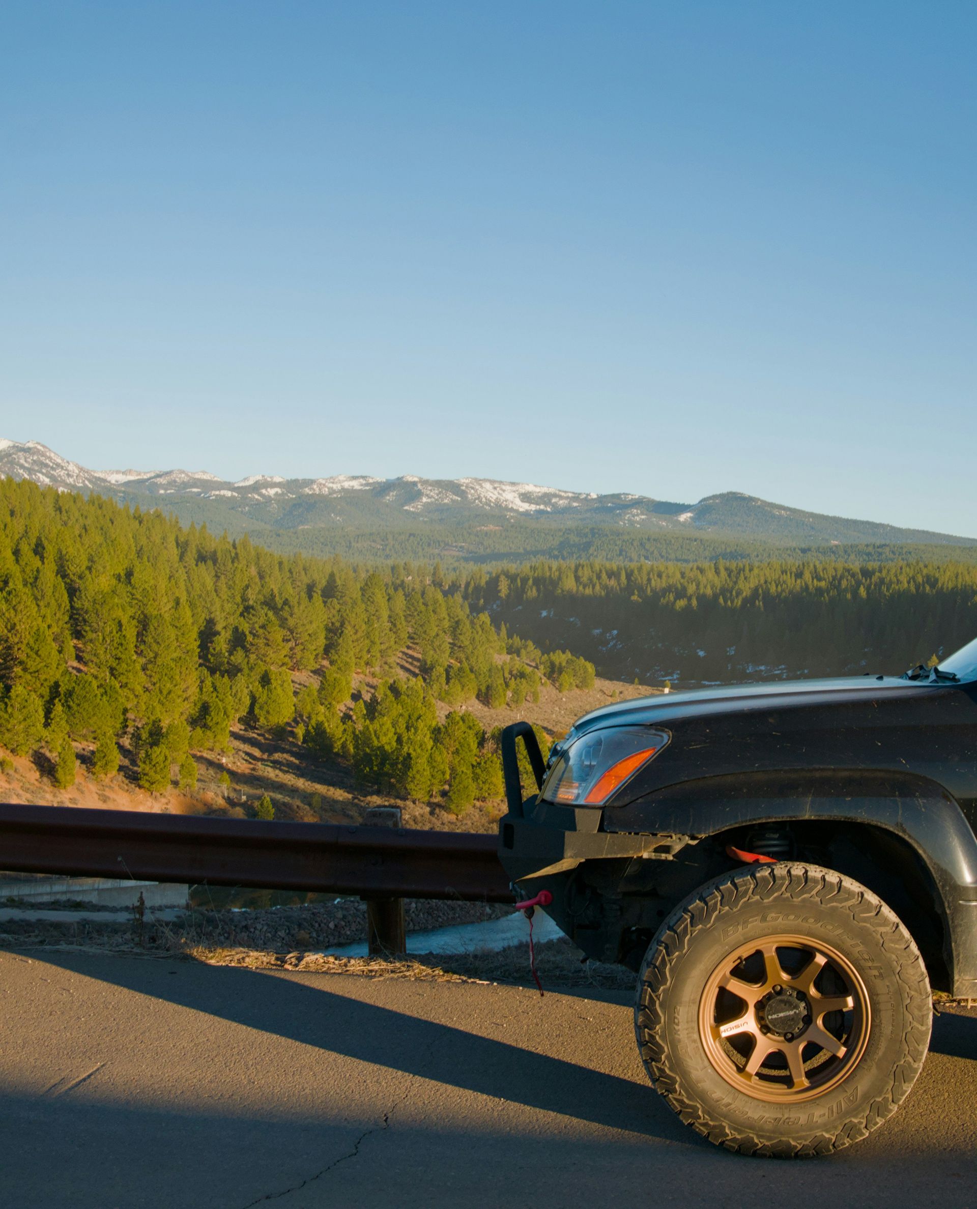 Off-road suv parked by a guardrail with mountains.